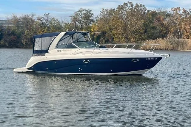 The Image of 2005 Rinker Fiesta Vee 320 boat on calm water, surrounded by trees. - 0