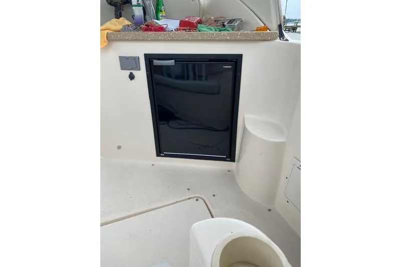 Slide: The Image of 2005 Rinker Fiesta Vee 320 boat interior with a compact refrigerator and countertop. - 12