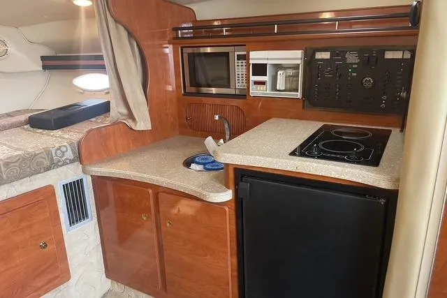 Slide: The Image of 2005 Rinker Fiesta Vee 320 cabin kitchen with microwave, stove, and fridge. - 15