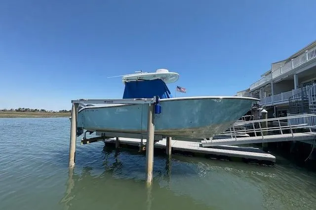 The Image of 2019 Cobia 280 Center Console boat on lift by dock, clear sky background. - 0