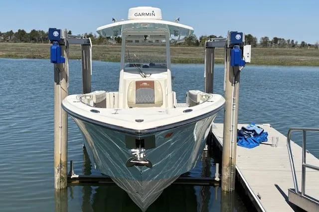 Slide: The Image of 2019 Cobia 280 Center Console boat on lift at dock, equipped with Garmin technology. - 10