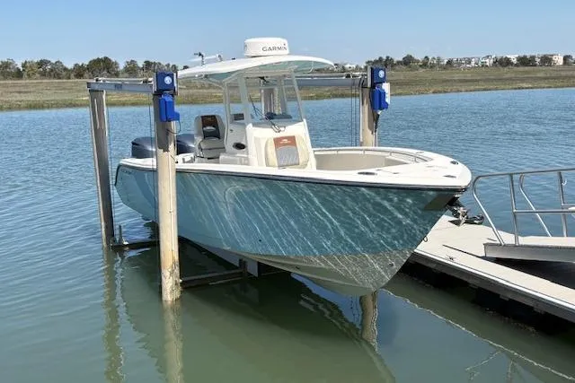 Slide: The Image of 2019 Cobia 280 Center Console boat on lift, docked in calm waters. - 11