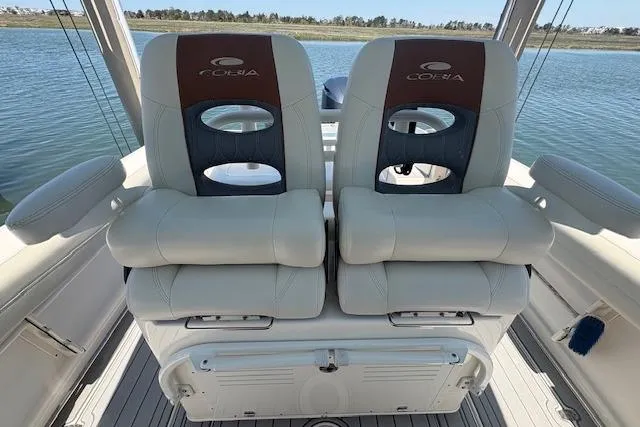 Slide: The Image of 2019 Cobia 280 Center Console boat seats with logo, on calm water background. - 25