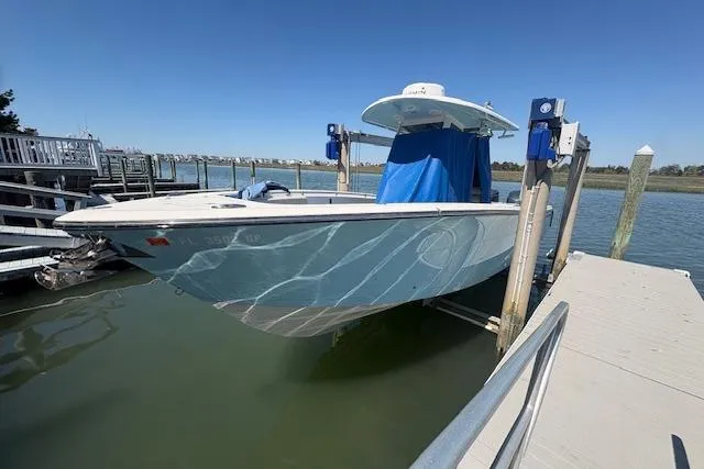 Slide: The Image of 2019 Cobia 280 Center Console boat docked on a lift in a marina. - 29