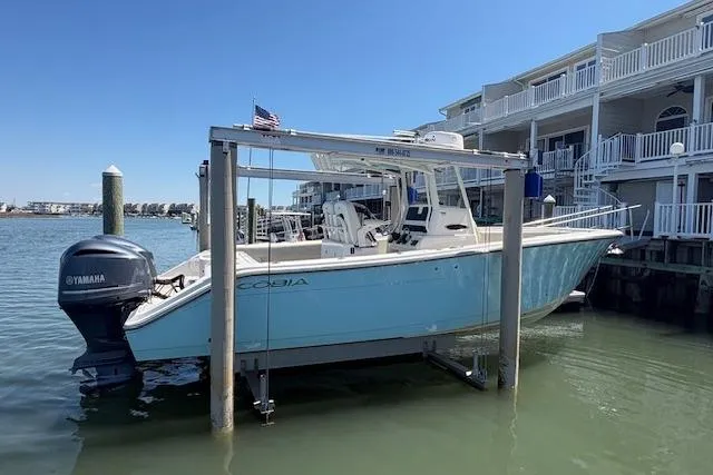 Slide: The Image of 2019 Cobia 280 Center Console boat docked near waterfront homes, featuring Yamaha engines. - 5