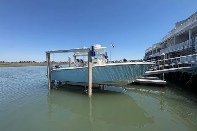 Slide: The Image of 2019 Cobia 280 Center Console boat docked on a lift by waterfront homes. - 6
