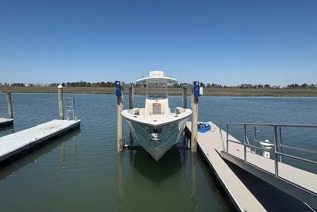Slide: The Image of 2019 Cobia 280 Center Console boat docked on calm water under clear blue sky. - 9