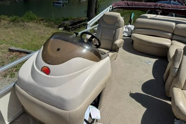 Slide: The Image of 2008 Sun Tracker Party Barge 25 Regency Edition with beige seating and helm, docked by a lake. - 4