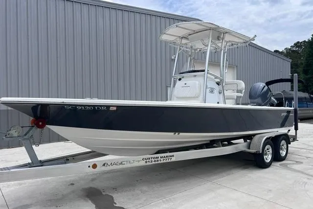 Slide: The Image of 2021 Sportsman Tournament 234 SBX Bay Boat on trailer, parked outside a metal building. - 20
