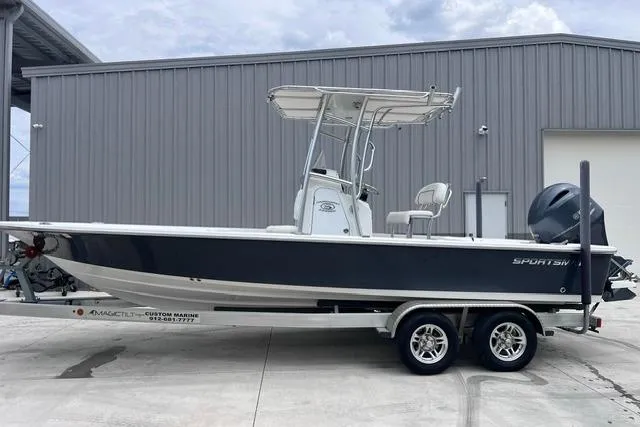 Slide: The Image of 2021 Sportsman Tournament 234 SBX Bay Boat on trailer, parked near a metal building. - 21