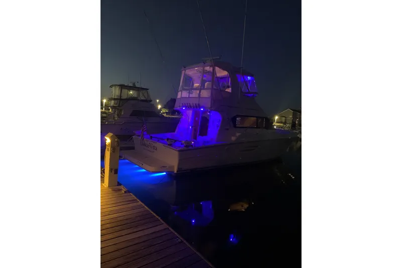 Slide: The Image of 2002 Silverton 42 Convertible yacht illuminated with blue lights at night in a marina. - 13