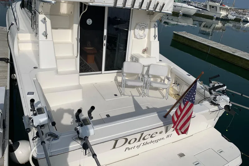 Slide: The Image of 2002 Silverton 42 Convertible yacht docked, featuring fishing gear and American flag. - 6