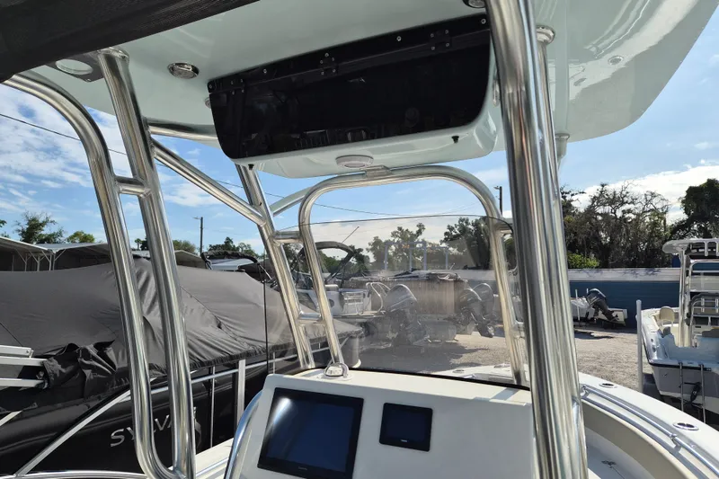 Slide: The Image of 2026 Key West 239 FS boat interior with console and T-top, parked outdoors. - 9