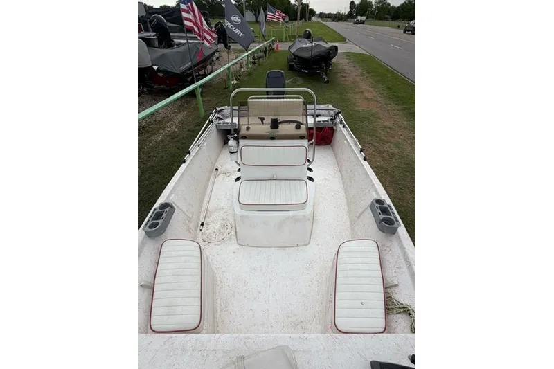 Slide: The Image of 2003 Kenner 18-V boat interior with white seating and cup holders, parked roadside. - 6