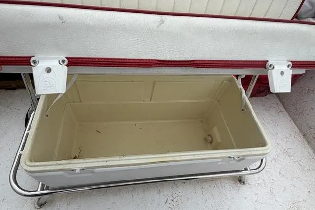 Slide: The Image of Open storage compartment on a 2003 Kenner 18-V boat, featuring a white and red cushioned lid. - 8