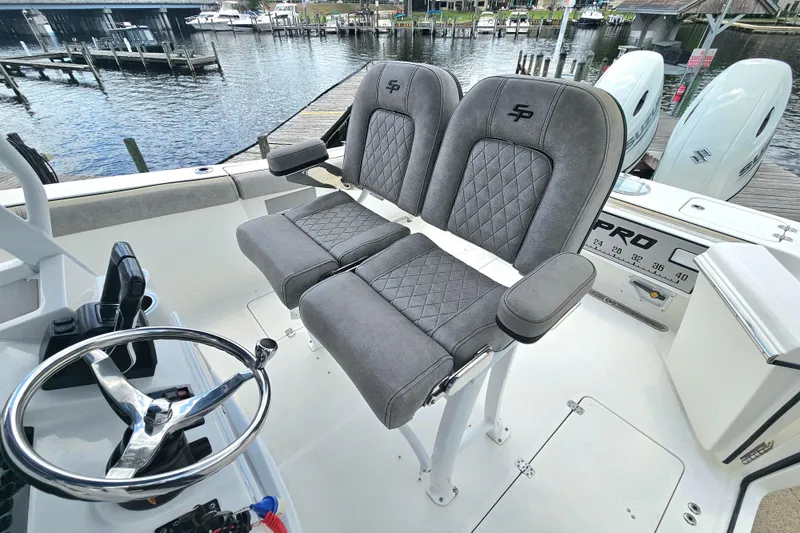 Slide: The Image of 2021 Sea Pro 259 Center Console boat with dual seats and steering wheel, docked by the water. - 14