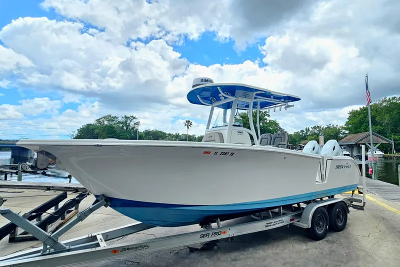 Slide: The Image of 2021 Sea Pro 259 Center Console boat on trailer by waterfront under cloudy sky. - 29