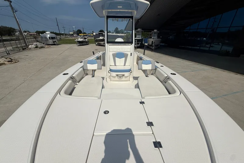 Slide: The Image of 2023 Robalo 246 Cayman boat, spacious deck, modern design, outdoor showroom setting. - 10