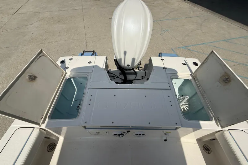 Slide: The Image of 2023 Robalo 246 Cayman boat deck with open storage compartments and motor. - 13