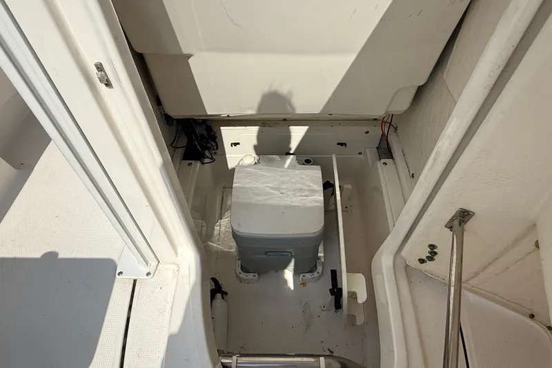 Slide: The Image of 2023 Robalo 246 Cayman boat interior with storage compartment and portable toilet. - 19