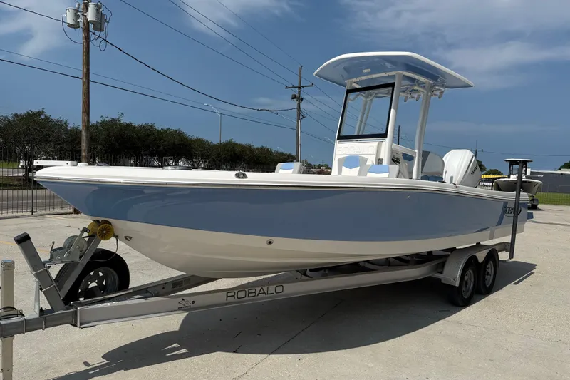 Slide: The Image of 2023 Robalo 246 Cayman boat on trailer, parked outdoors under clear sky. - 3