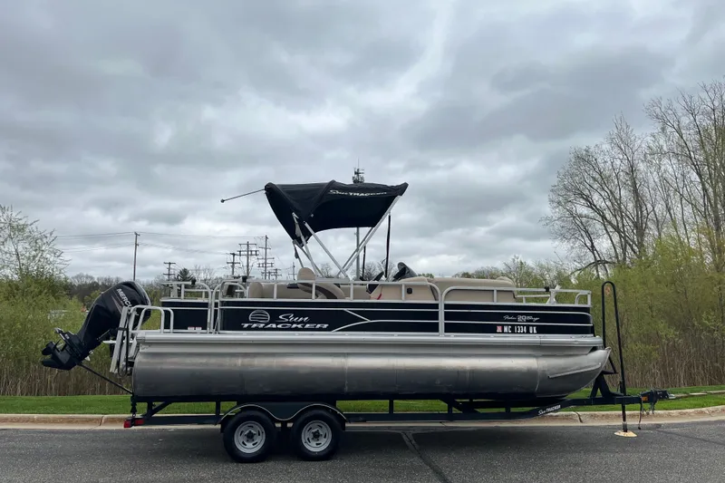 The Image of 2016 Sun Tracker Fishin' Barge 20 DLX pontoon boat on trailer, overcast sky. - 0