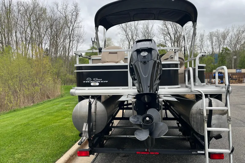 Slide: The Image of 2016 Sun Tracker Fishin' Barge 20 DLX pontoon boat with outboard motor, parked outdoors. - 2