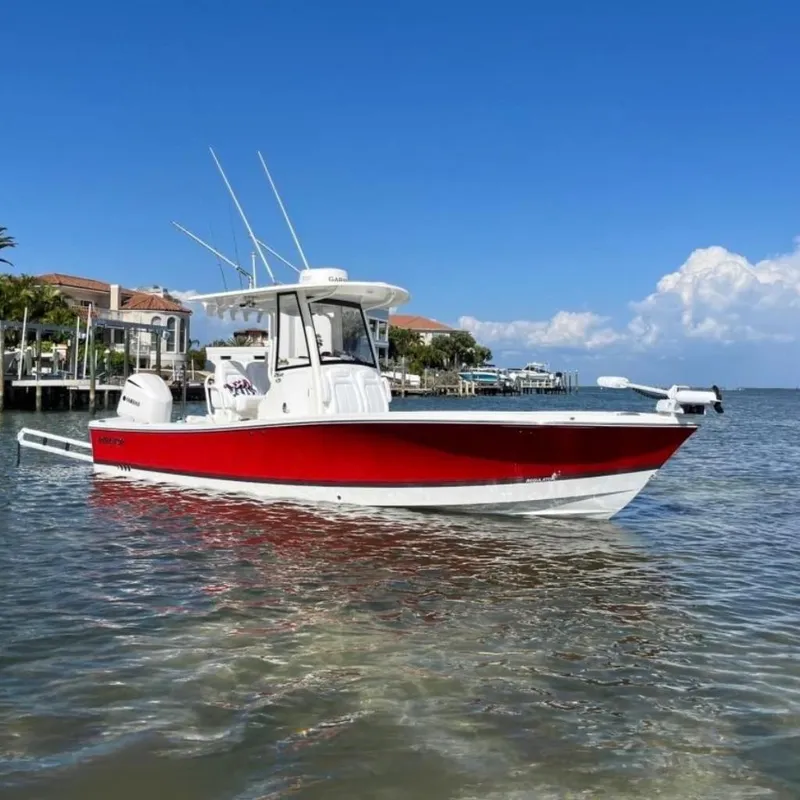 The Image of 2019 Regulator 26XO boat with red hull on calm water, clear blue sky background. - 0