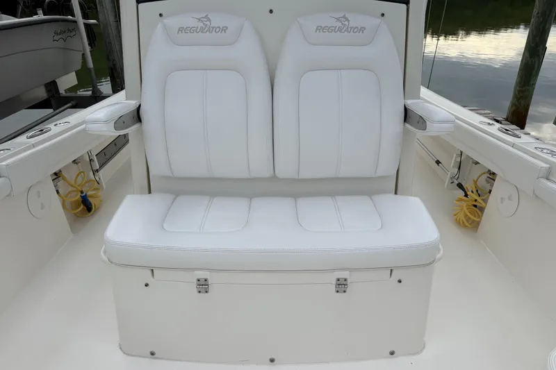 Slide: The Image of 2019 Regulator 26XO boat with white cushioned seating and armrests, docked by the water. - 17
