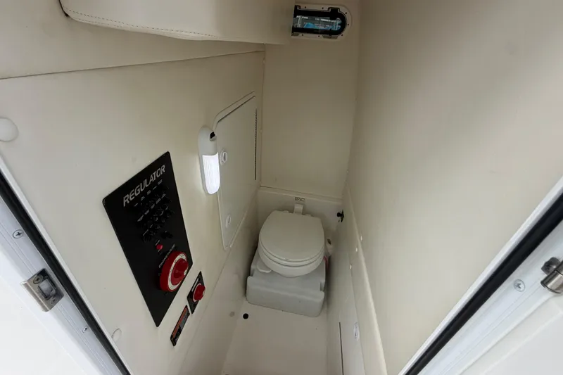 Slide: The Image of 2019 Regulator 26XO boat interior with compact marine toilet and control panel. - 23