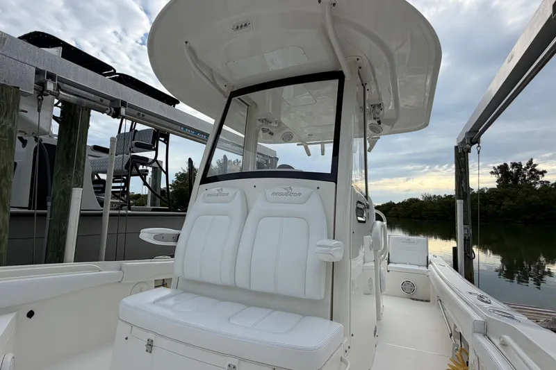 Slide: The Image of 2019 Regulator 26XO boat with white seating and console, docked by calm waters. - 24