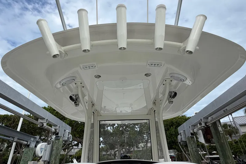 Slide: The Image of 2019 Regulator 26XO boat's T-top with rod holders and speakers, docked under a cloudy sky. - 26