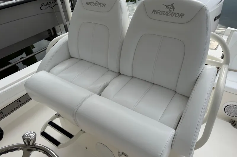 Slide: The Image of 2019 Regulator 26XO boat with white cushioned seating and steering wheel. - 32