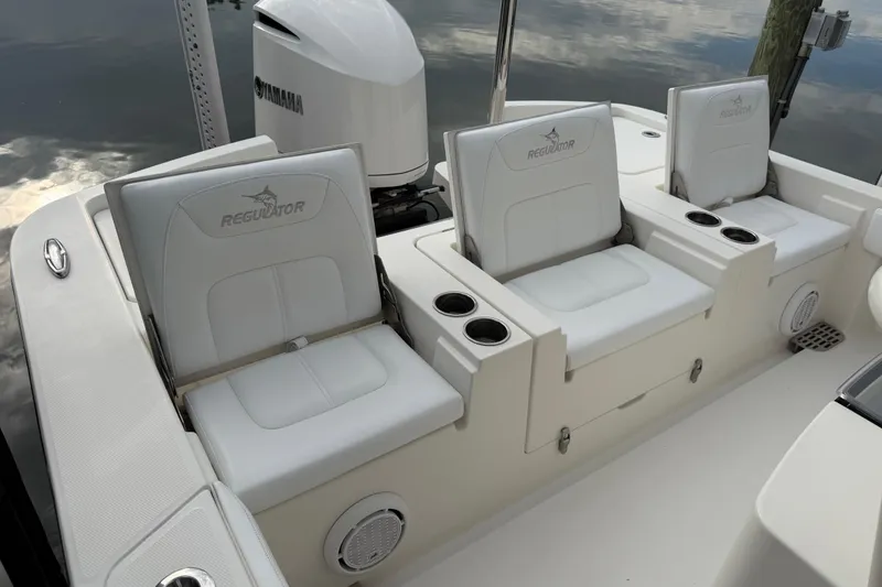 Slide: The Image of 2019 Regulator 26XO boat seating area with Yamaha engine, featuring comfortable white seats and cup holders. - 36