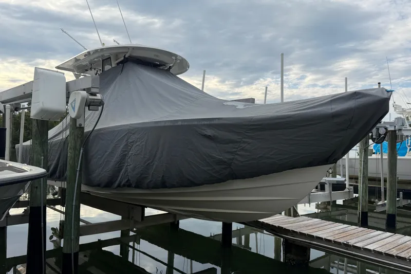 Slide: The Image of 2019 Regulator 26XO boat covered and docked at a marina. - 48