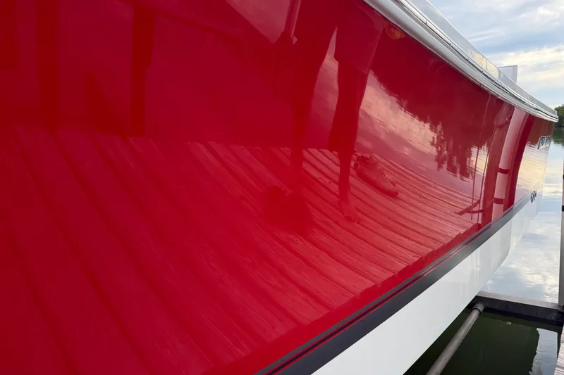 Slide: The Image of Shiny red hull of a 2019 Regulator 26XO boat reflecting dock and water. - 5