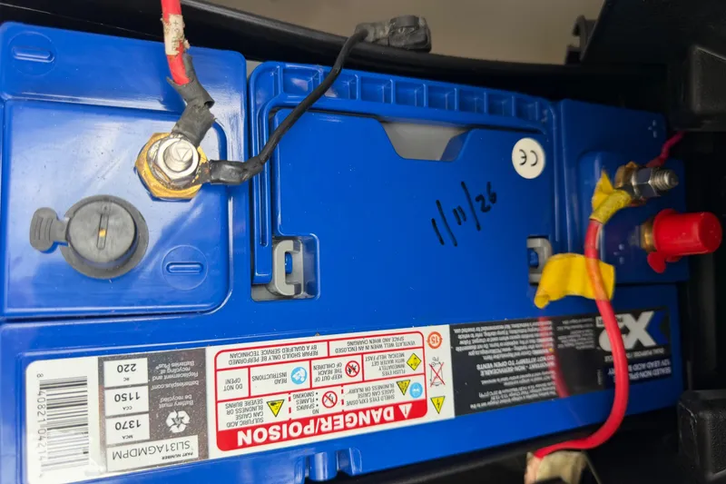 Slide: The Image of Close-up of a blue battery in a 2019 Regulator 26XO boat, showing wiring and safety labels. - 55