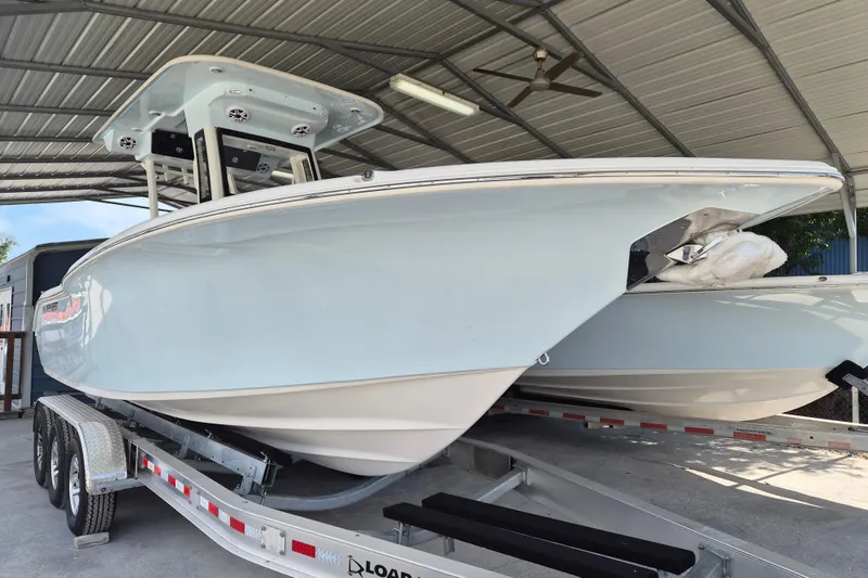 The Image of 2026 Key West 260 Center Console boat on trailer under metal canopy. - 1