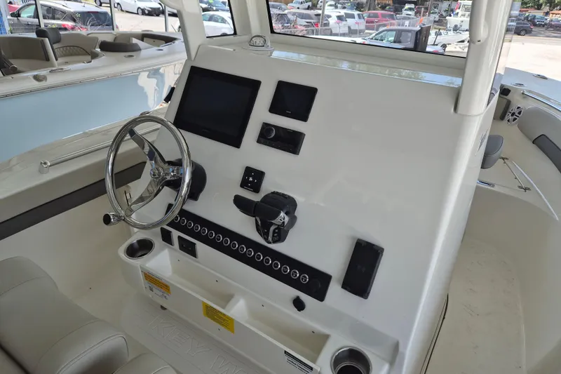 Slide: The Image of 2026 Key West 260 Center Console boat dashboard with steering wheel and electronic controls. - 13
