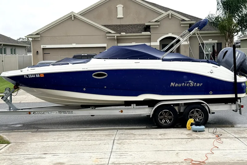 The Image of 2020 NauticStar 243 DC boat on trailer in residential driveway. - 1