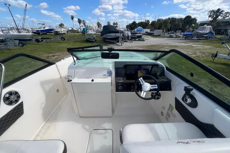 Slide: The Image of 2019 Sea Ray SDX 250 Outboard boat interior with steering wheel and dashboard, parked outdoors. - 6
