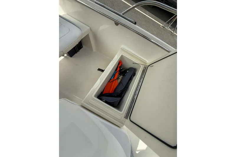 Slide: The Image of 2012 Boston Whaler 150 Super Sport boat storage compartment with life jackets and gear. - 10
