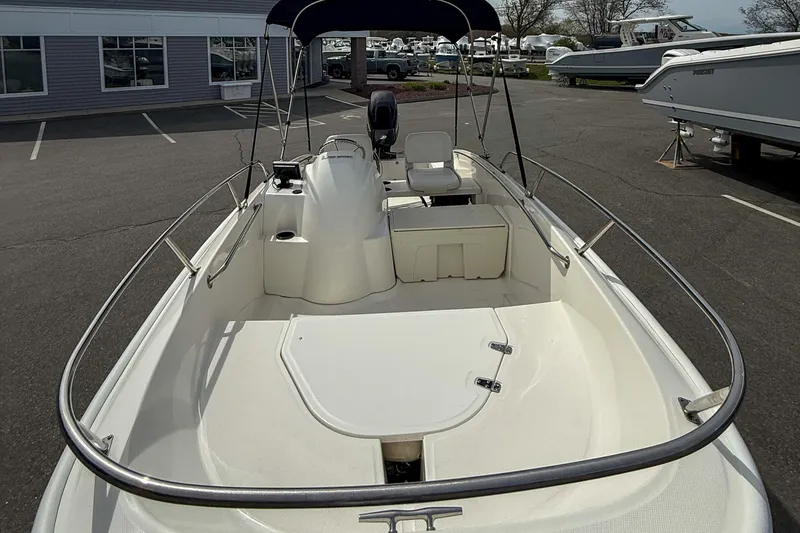 Slide: The Image of 2012 Boston Whaler 150 Super Sport boat with seating and canopy in a parking lot. - 12