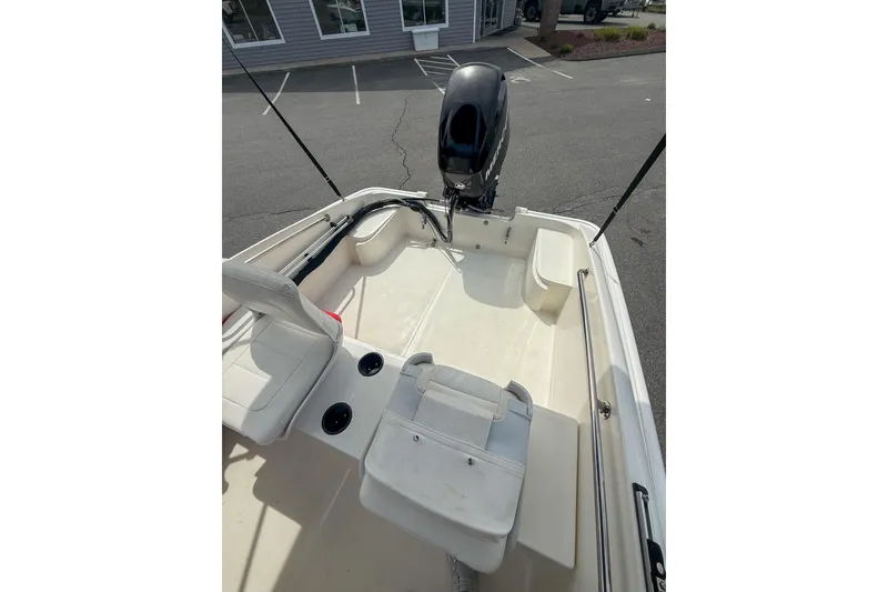 Slide: The Image of 2012 Boston Whaler 150 Super Sport boat interior with seating and motor, parked outdoors. - 6