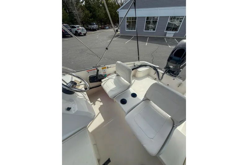 Slide: The Image of 2012 Boston Whaler 150 Super Sport boat interior with white seating and steering wheel. - 7