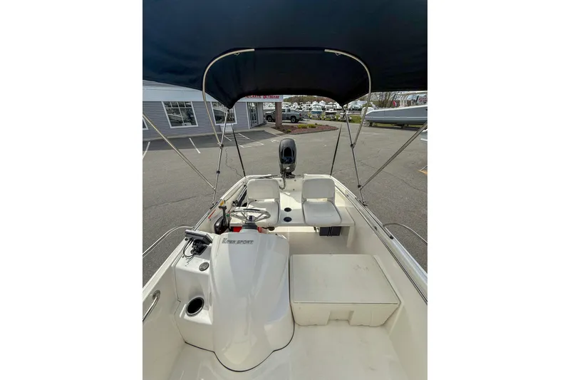 Slide: The Image of 2012 Boston Whaler 150 Super Sport boat interior with canopy, parked outdoors. - 9