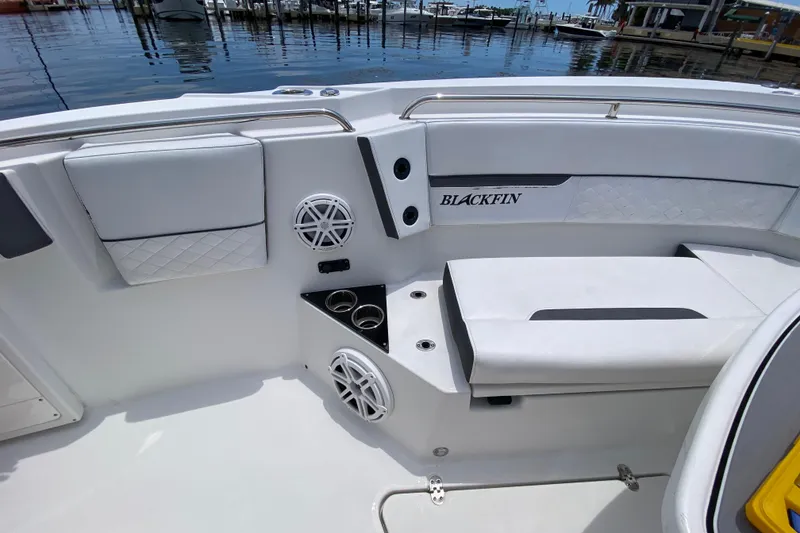 Slide: The Image of 2022 Blackfin 332 CC boat interior with cushioned seating and cup holders by the water. - 25