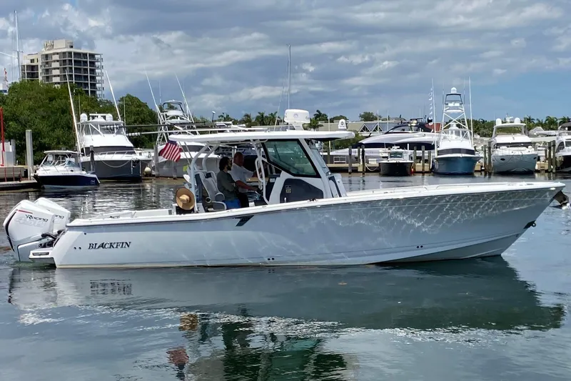 The Image of 2022 Blackfin 332 CC boat docked in marina with people onboard, surrounded by other boats. - 0