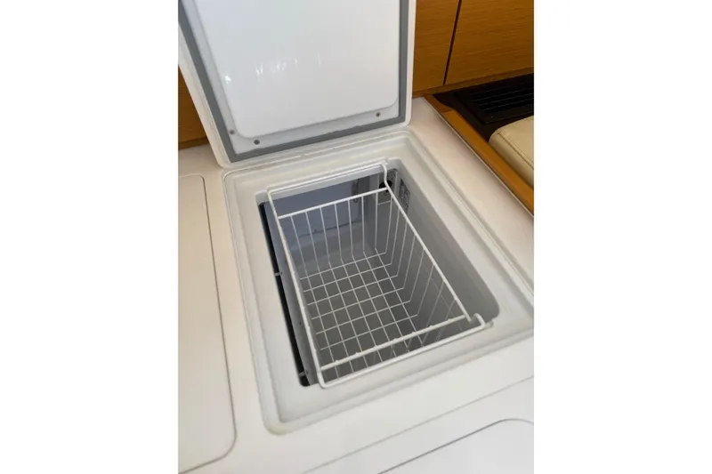 Slide: The Image of Open storage compartment on 2018 Jeanneau 58 yacht, featuring a wire basket. - 10