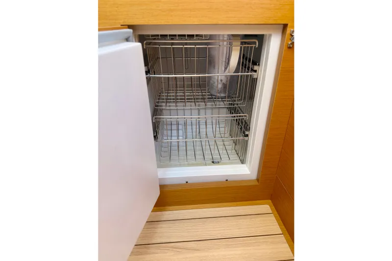 Slide: The Image of Open refrigerator in 2018 Jeanneau 58 yacht, showcasing wire shelving and wooden flooring. - 11